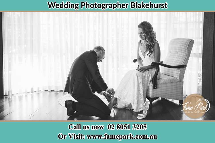 The Bride is being helped by the Groom trying to put on her shoes Blakehurst NSW 2221