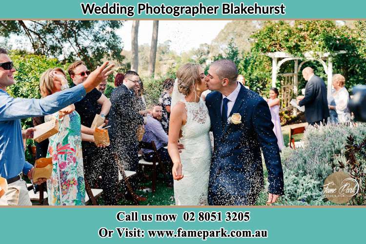 Photo of the Bride and the Groom kissing while showering rice by their visitors Blakehurst NSW 2221