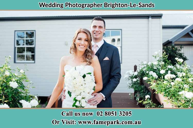 The Bride and the Groom smiling on camera at the front of the house Brighton-Le-Sands NSW 2216