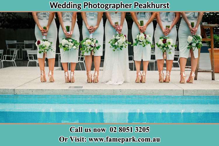 Behind photo of the Brides and the bridesmaids holding flower near the pool Peakhurst NSW 2210