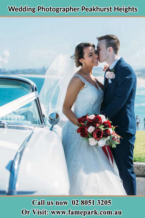 Photo of the Groom kissing the Bride beside the bridal car Peakhurst Heights NSW 2210